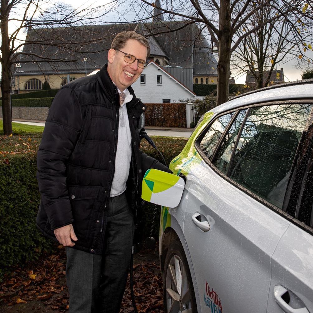 Wethouder Mark Gerritsen laadt een elektrische auto op aan een laadpaal.